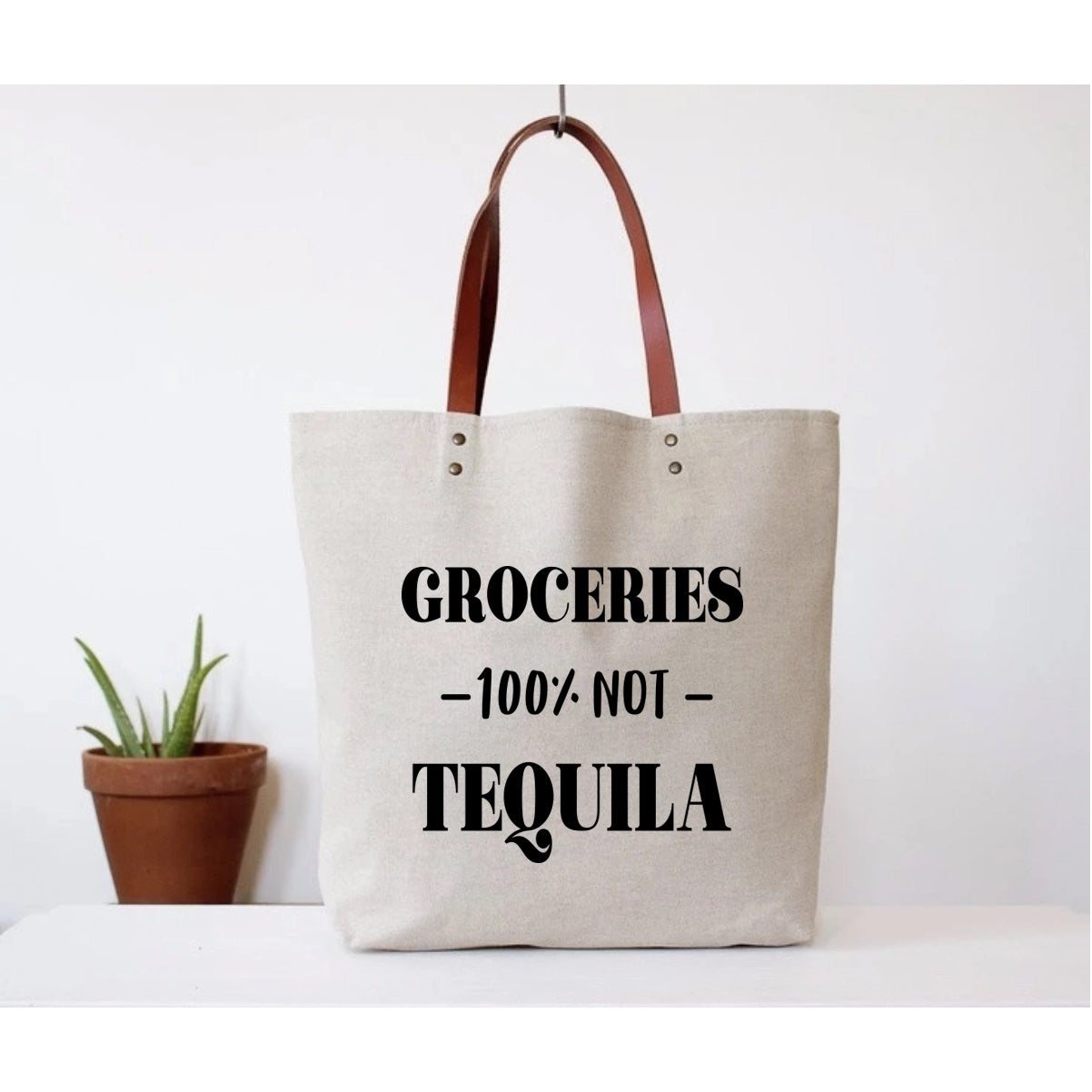 Canvas tote bag with faux leather straps that says "Groceries -100% NOT -Tequila"