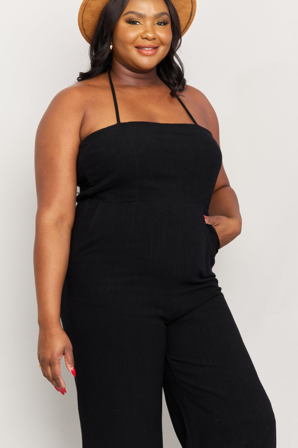 Woman modeling black halter neck wide leg jumpsuit.