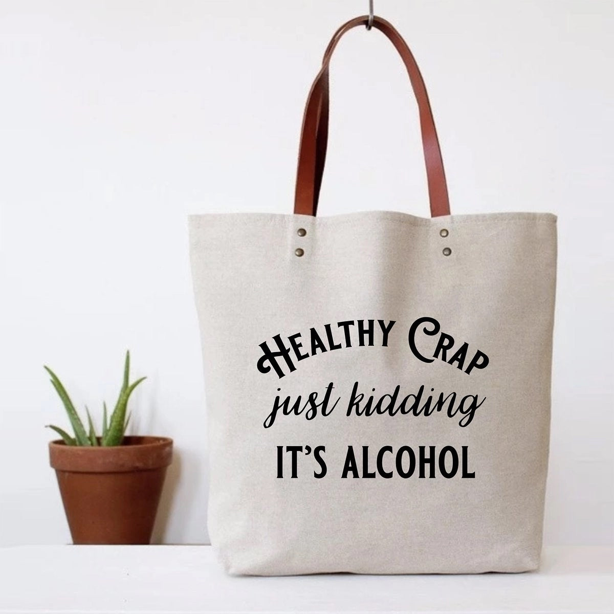 Canvas tote bag with faux leather straps that says "Healthy Crap Just kidding it's alcohol"
